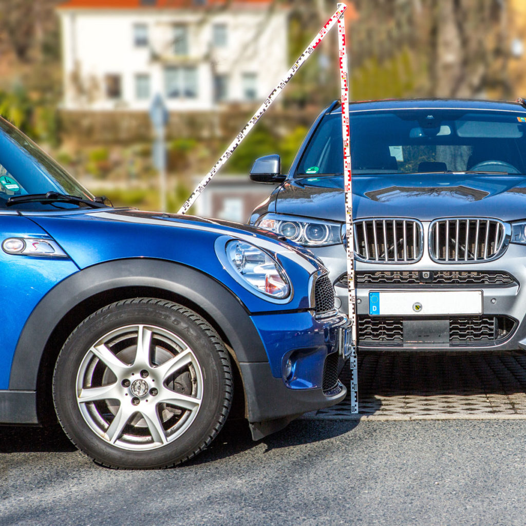 Zwei Autos die im 90°-Winkel zueinander stehen, Messlatte für die Überprüfung der Kompatibilität der Schäden