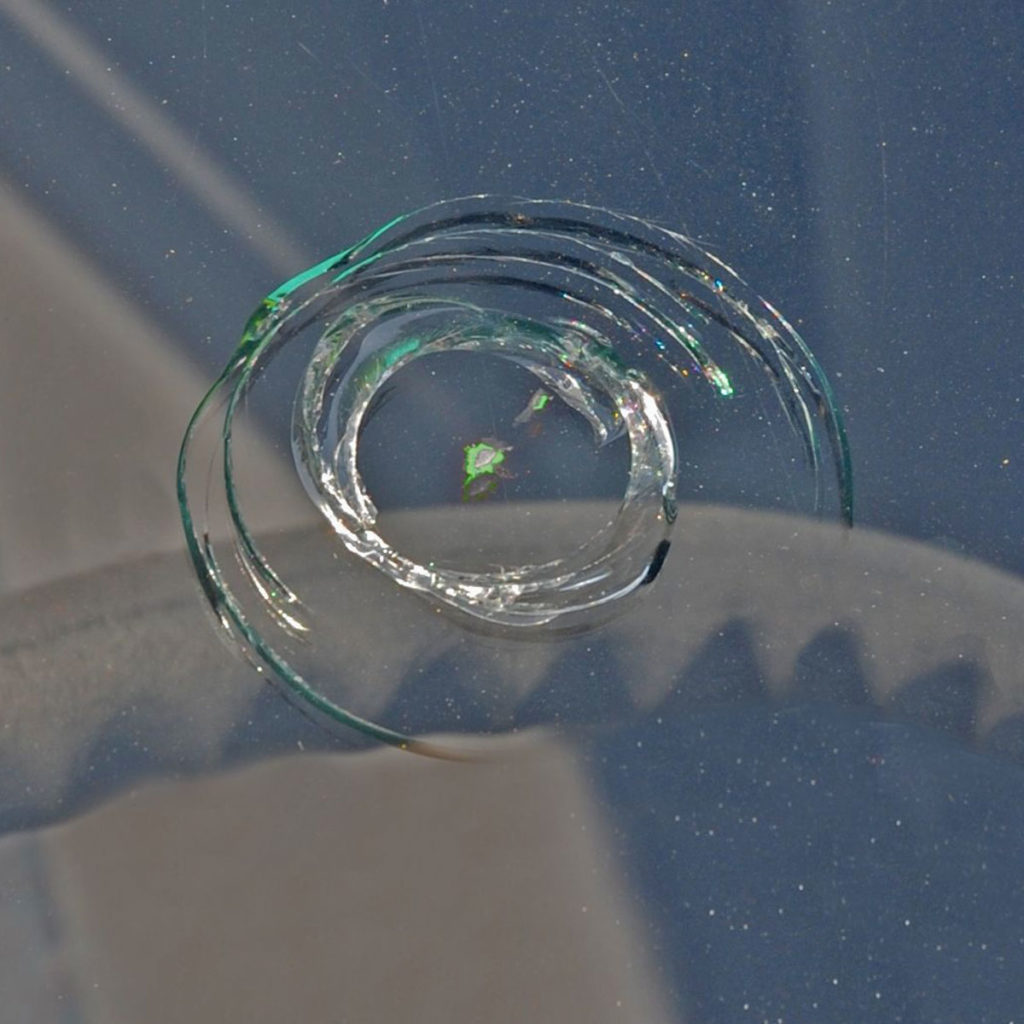Detail einer Autofrontscheibe, auf welcher das Glas in runder Form gesprungen ist durch einen Steinschlag